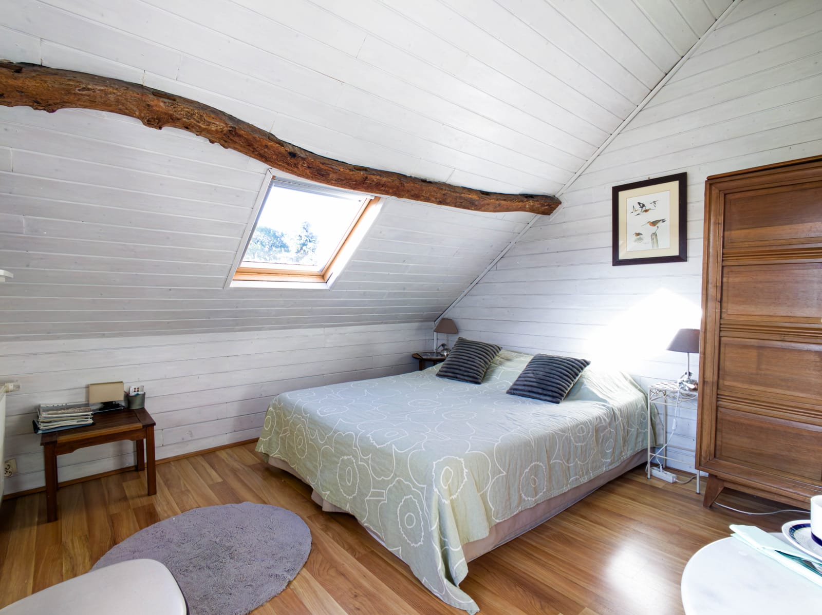 Chambre Barge sous les combles : grand lit double, poutre apparente, lambris blancs et fenêtre de toit