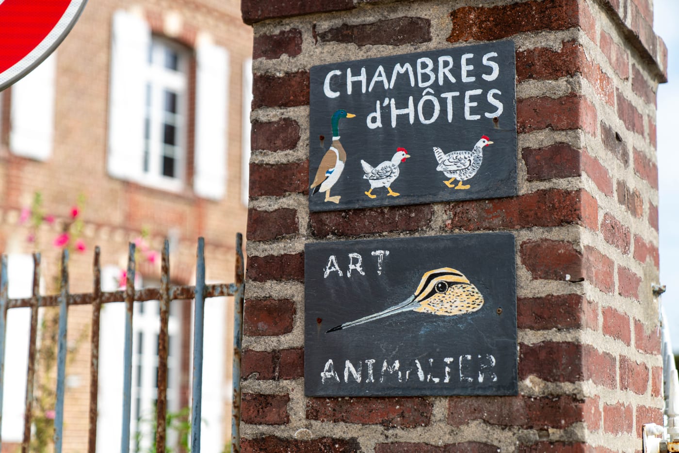 Pilier en brique à l'entrée, avec l'ardoise « Chambres d'hôtes » et une seconde ardoise « Art animalier »